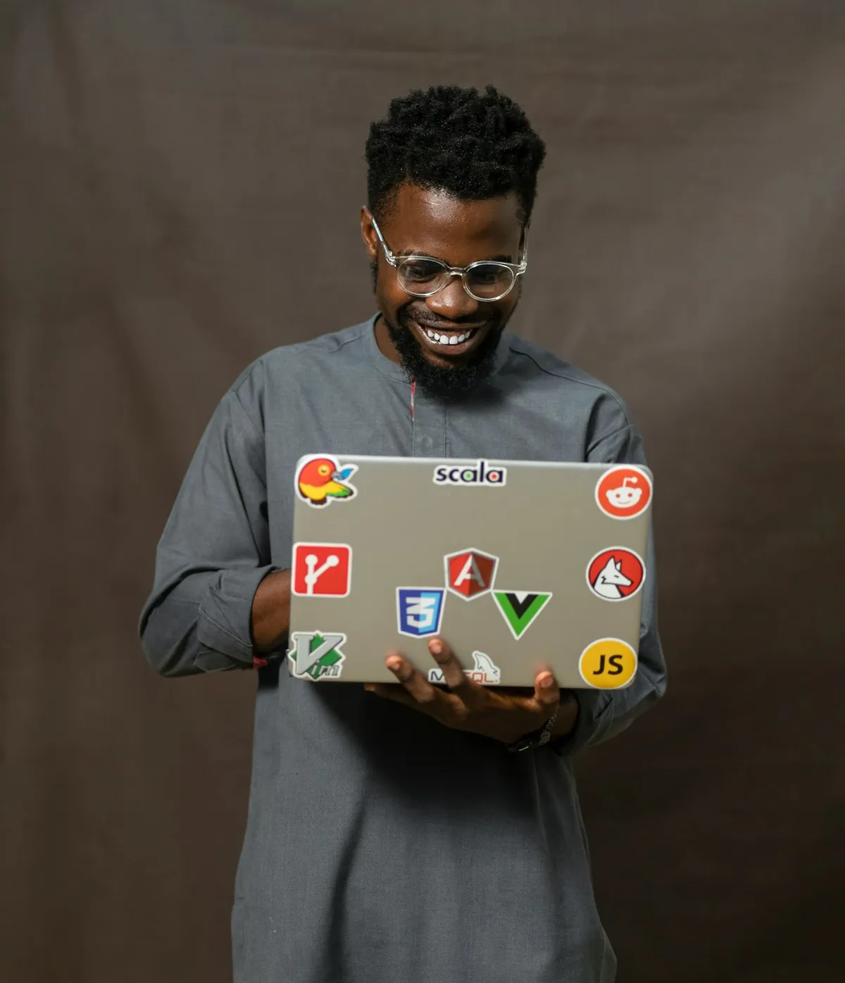 A developer holding a laptop covered in programming stickers