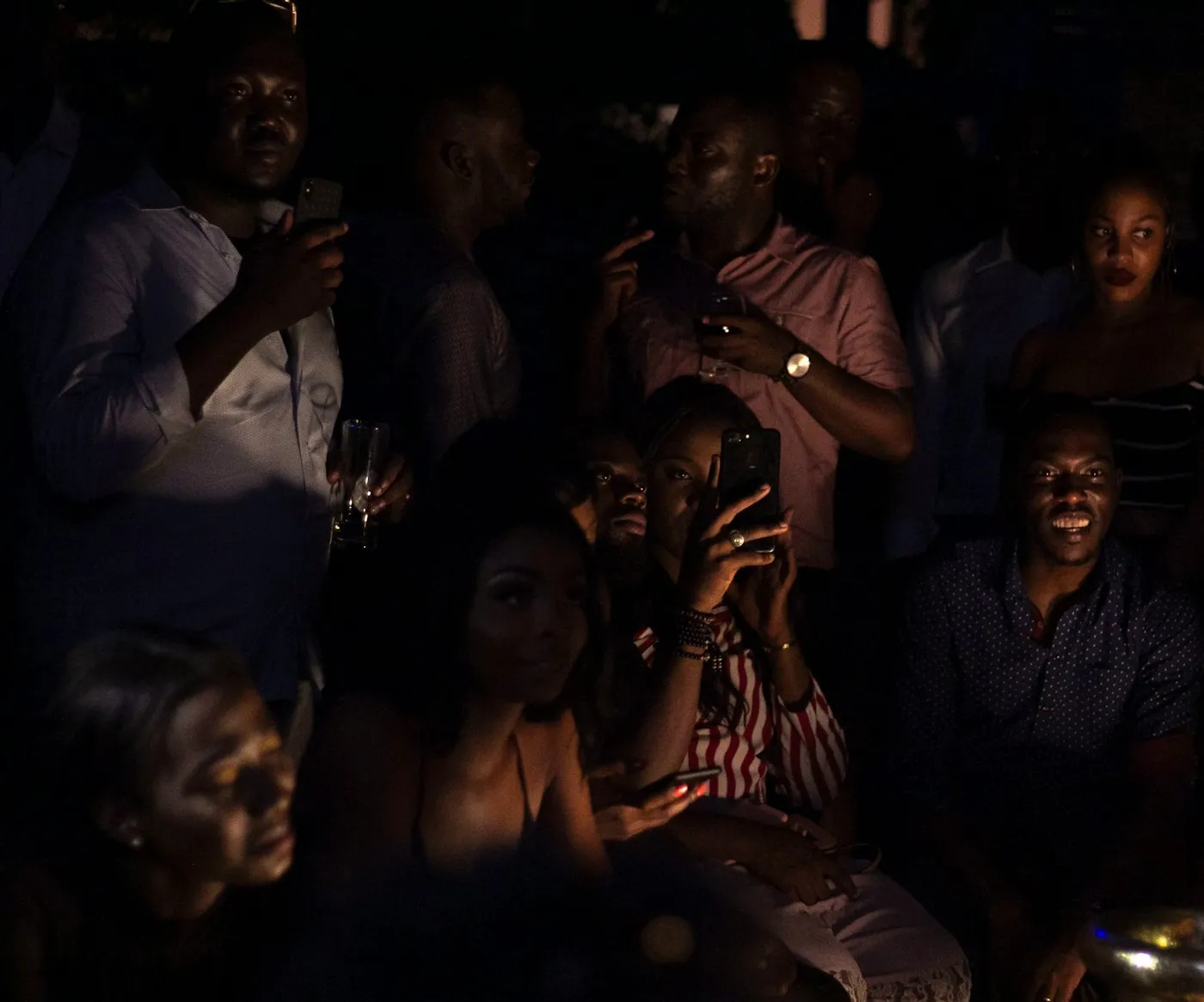 An audience in a darkened room, faces lit by the screen