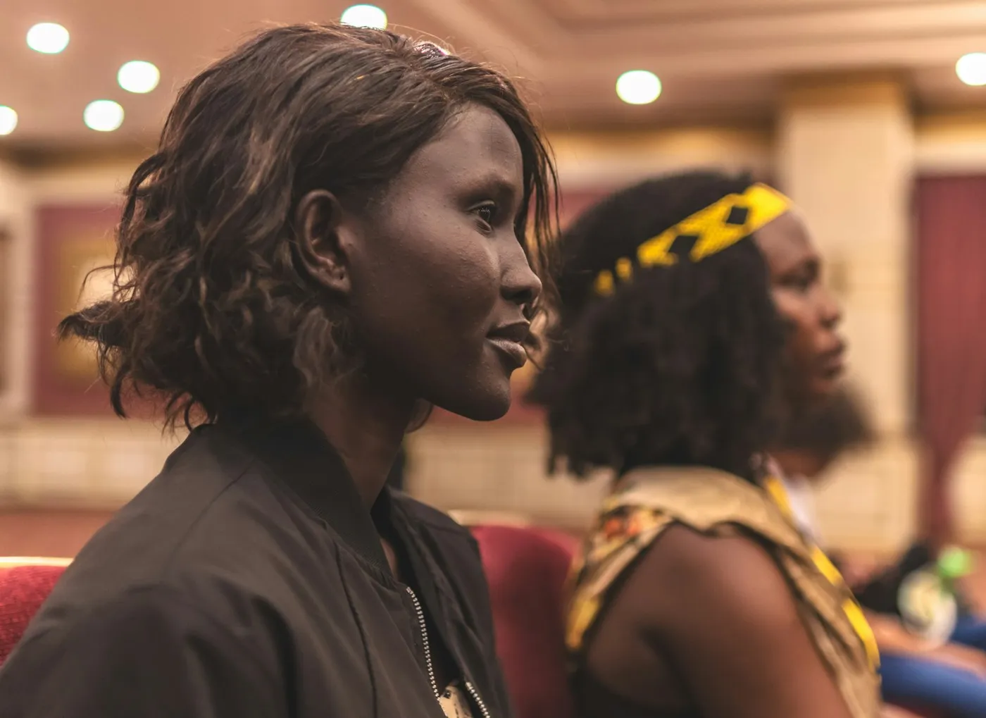 Two women in an audience, watching the front of the room